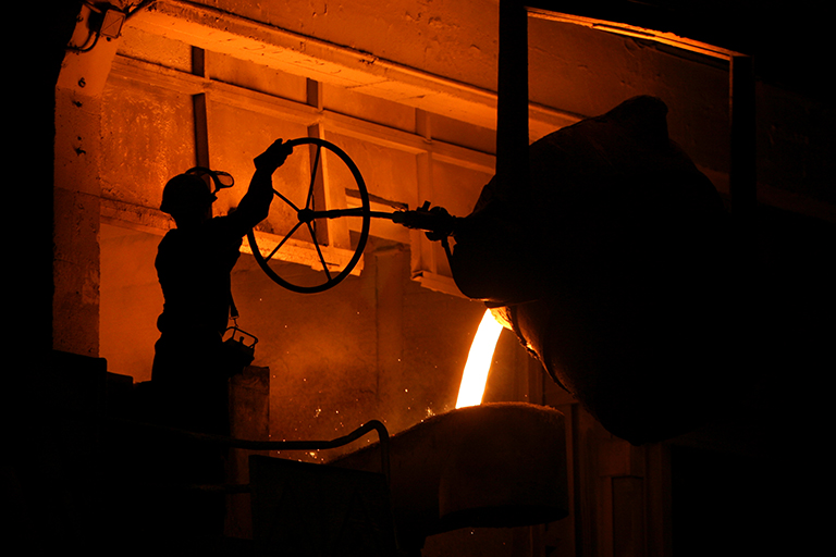 Foundry operator manipulating a valve while pouring molten metal
