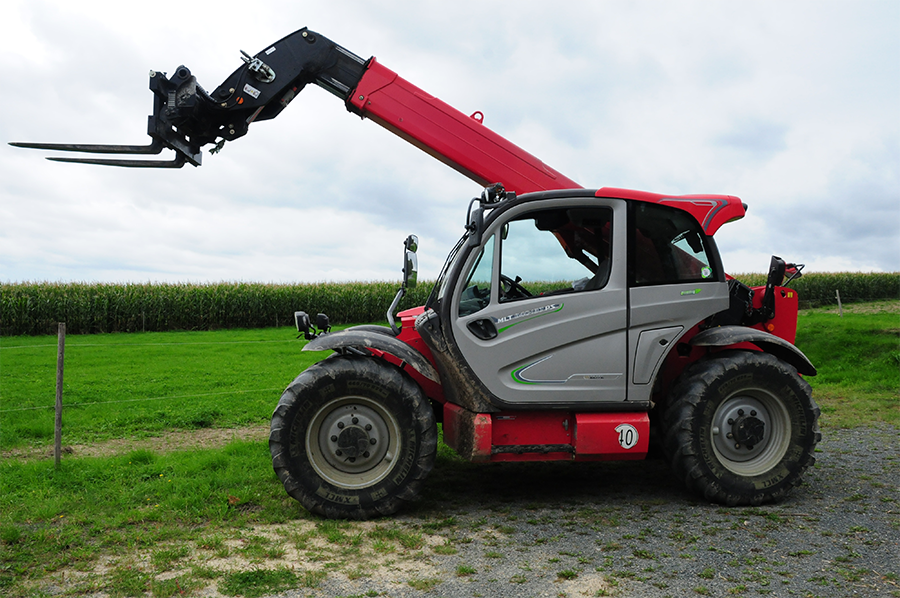 Red telescopic handler with forks parked in a rural setting