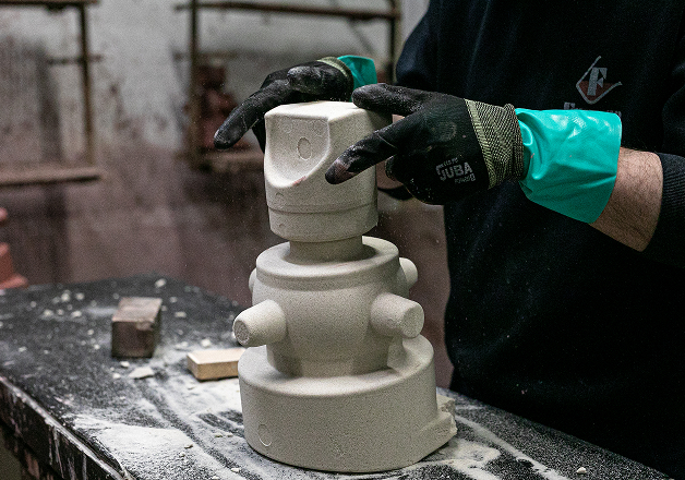 Craftsman working on stone sculpture wearing protective gloves.